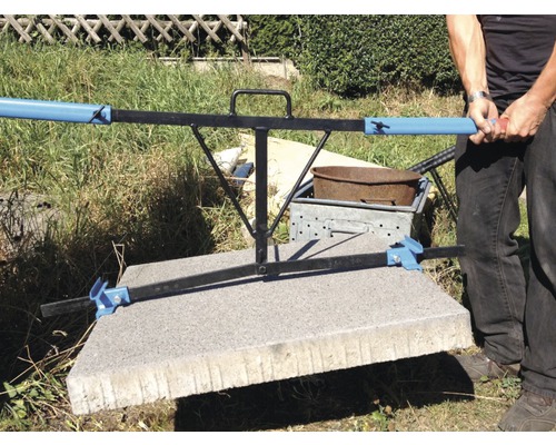 Des personnes transportent une dalle de béton avec un lève-pierre.