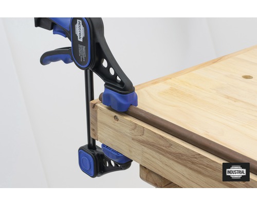 Serre-joint à tige fixant une pièce sur un établi.