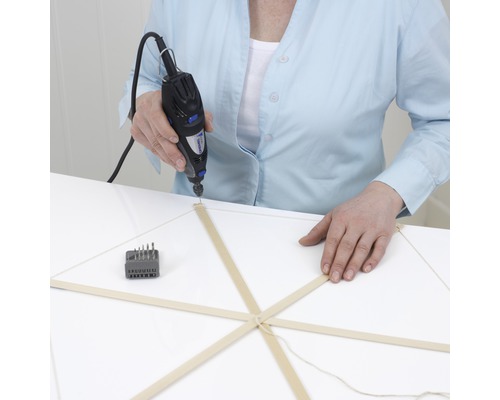 Une personne perce un modèle en bois avec un outil multifonction Dremel.