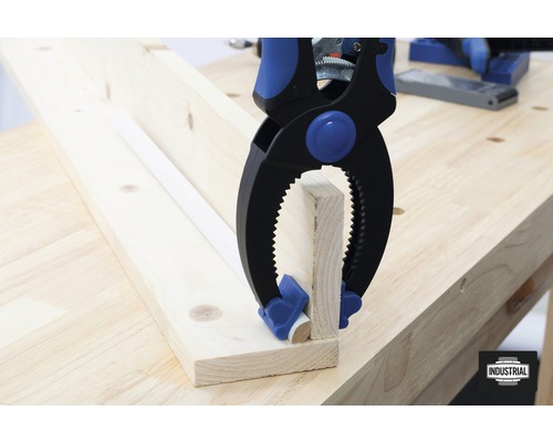 La pince à ressort fixe les pièces de bois sur un établi.