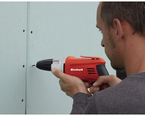 Mann schraubt mit einem Einhell Akkuschrauber eine Schraube in eine Gipskartonwand