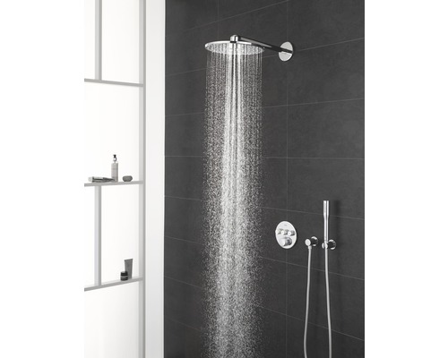 Douche à effet pluie avec jet d''eau et robinetterie sur un mur sombre dans la salle de bain.