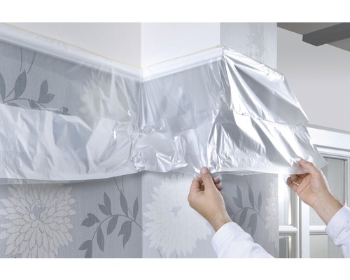 Abdeckfolie wird an einer Wand mit floraler Tapete angebracht