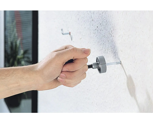 Eine Person befestigt einen Dübel mit einem Montagewerkzeug an einer Wand