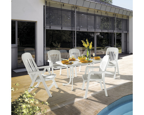 Gartenszene mit einem weißen Gartentisch und sechs Stühlen auf einer Terrasse.