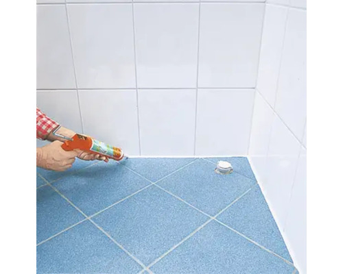 Anwendung von Dichtstoff in einem Badezimmer mit blauen Bodenfliesen und weißen Wandfliesen