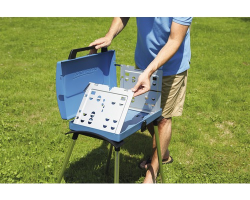 Un homme assemble un barbecue de camping bleu à l''extérieur