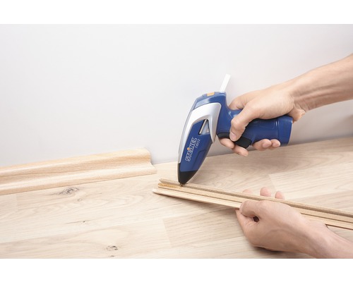 Pistolet à colle chaude collant des plinthes en bois
