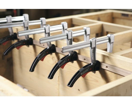 Mehrere Einhandzwingen fixieren ein Holzwerkstück.