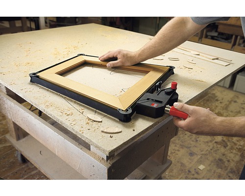 Cadre en bois fixé avec une pince de cadre sur un établi.