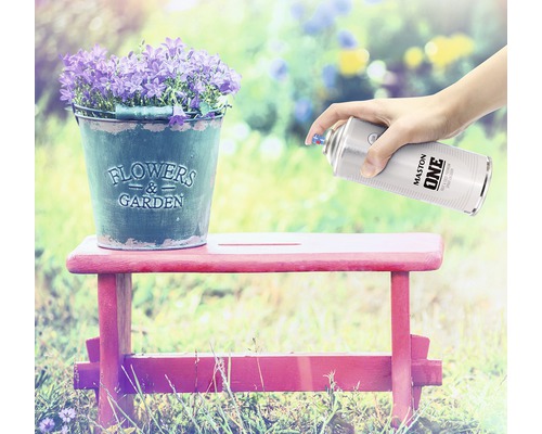 Scène avec des fleurs dans un seau en zinc sur un tabouret, qui est pulvérisé avec un aérosol de peinture.