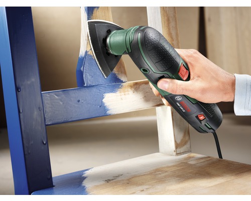 Outil multifonction oscillant ponçant la surface d''une chaise en bois.