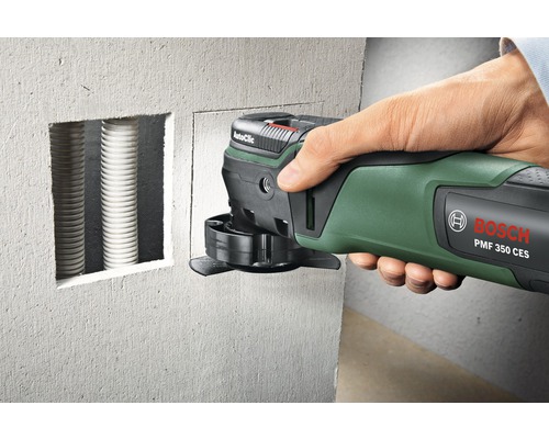 Outil multifonction Bosch en cours d''utilisation pour découper des encoches dans un mur pour l''installation de tuyaux