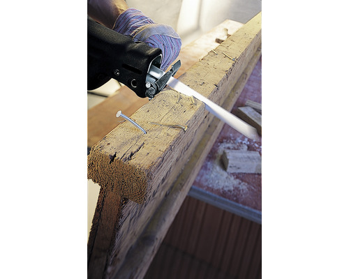 Une scie sauteuse coupe une planche de bois avec des clous.