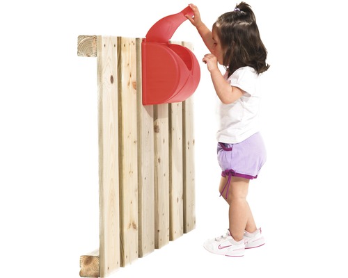 Enfant joue avec une boîte aux lettres jouet rouge sur un mur en bois