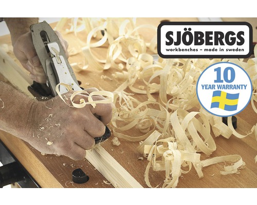 Un homme rabote du bois sur un établi Sjöbergs, entouré de copeaux de bois. Logo Sjöbergs. Sceau de garantie de 10 ans.