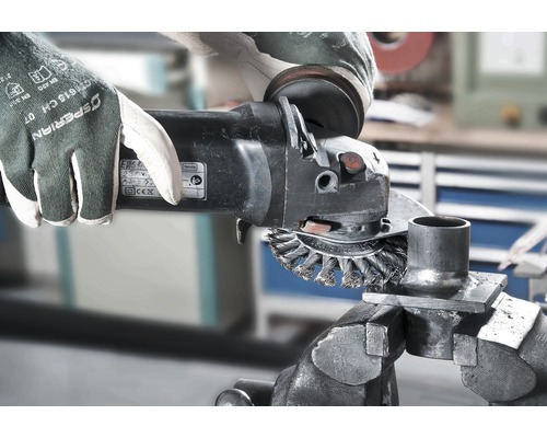 Artisan avec des gants de protection et une meuleuse d''angle travaillant le métal dans un atelier