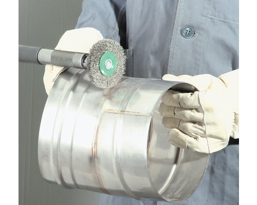 Une personne utilise une brosse métallique pour nettoyer un tuyau métallique.