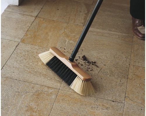 Brosse avec manche en bois pour nettoyer un sol carrelé
