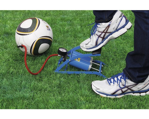 Une personne gonfle un ballon de foot avec une pompe à pied sur une pelouse.