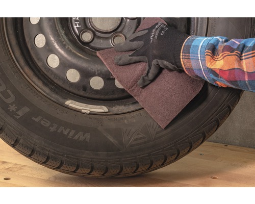 Une personne ponce un pneu avec du papier de verre.