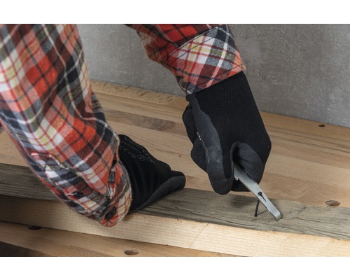 Person entfernt einen Nagel aus einem Holzbrett mit einem Nagelheber