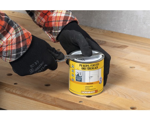 Eine Person mit Handschuhen öffnet eine Dose PU Acryl Fenster- und Türenlack mit einem Werkzeug der Marke Hornbach.