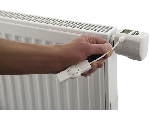 Person schliesst ein Heizkörperthermostat mit einem USB-Kabel an einen Heizkörper an