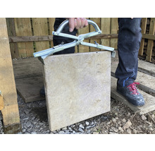 Mann hebt Gehwegplatte mit Steinzange