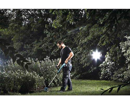 Un homme travaille dans le jardin avec un coupe-bordure.