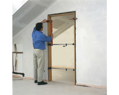 Mann montiert eine Tür mit einem Türspreizer in einem Rohbau