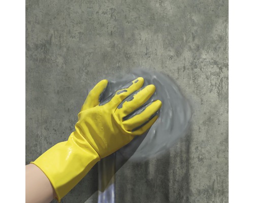 Gelbe Schutzhandschuhe reinigen eine graue Wand