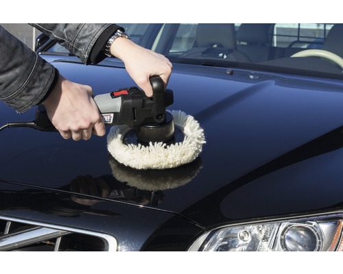 Un homme polit le capot d''une voiture avec une polisseuse.