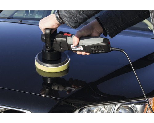 Une personne polit une voiture avec une polisseuse.