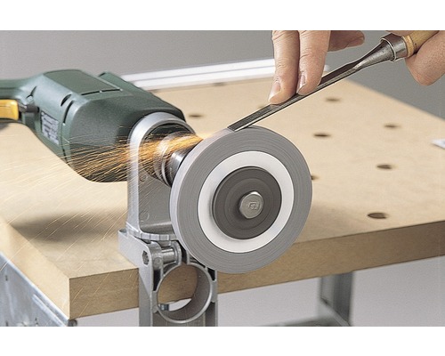 Une meule est fixée à une perceuse pendant qu''une personne y aiguise un ciseau à bois, ce qui produit des étincelles.