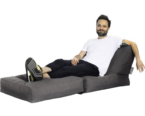 Homme se détend sur un pouf gris avec repose-pieds