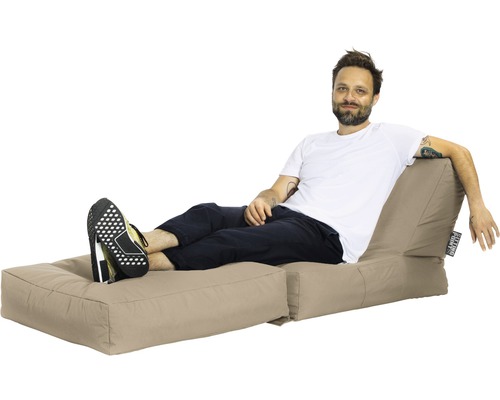 Mann entspannt sich auf einem beigen Sitzsack mit Fußteil