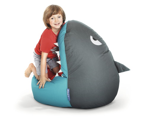 Junge klettert auf einen Sitzsack in Form eines Hais.