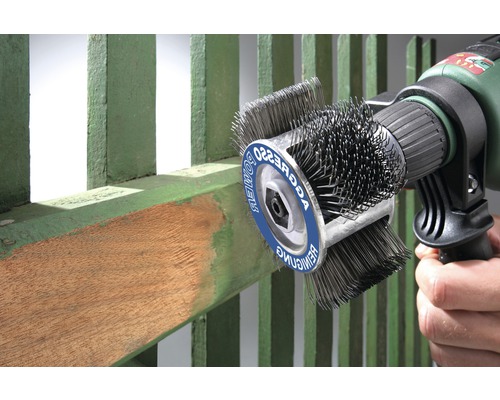 Brosse métallique fixée sur une perceuse nettoyant une clôture en bois