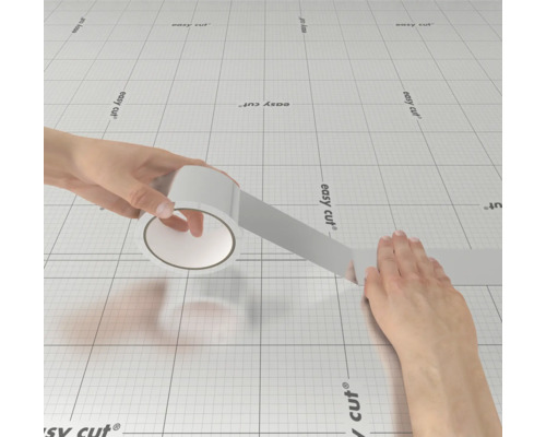 Un rouleau de ruban adhésif est déroulé sur un tapis de découpe.