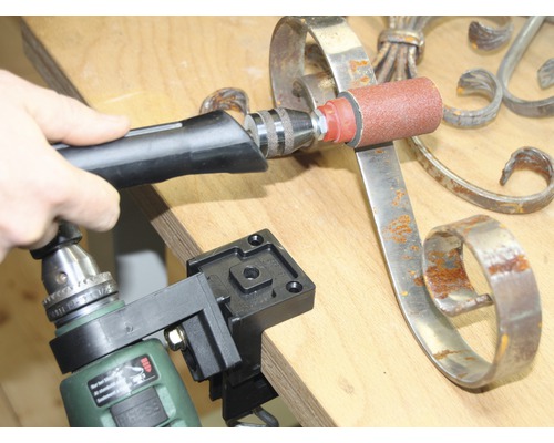 Person schleift Metall mit einem an einer Bohrmaschine befestigten Schleifwerkzeug