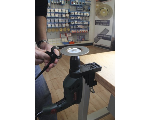 Person schärft Zange mit einem Schleifvorsatz auf einer Bohrmaschine.
