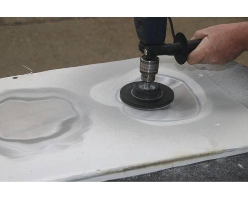Eine Person schleift mit einer Poliermaschine eine Oberfläche.