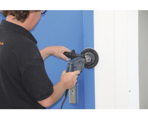 Eine Person verwendet eine Bohrmaschine mit Schleifaufsatz an einer Tür.