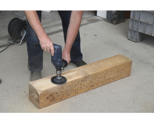 Eine Person schleift mit einem Schleifgerät ein Stück Holz.