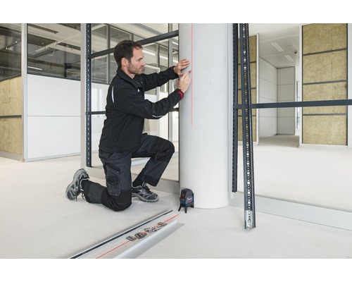 Artisan utilisant un laser lignes croisées lors du montage d'une sous-structure métallique en aménagement intérieur.