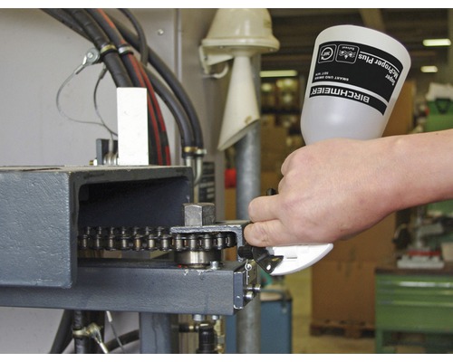 Person schmiert Kette an Maschine mit Schmieröl von Birchmeier