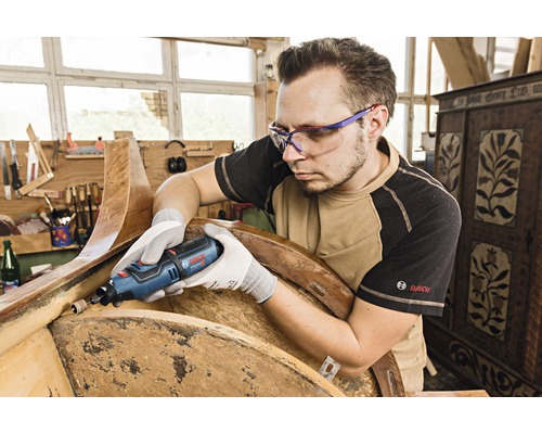 Un homme travaille un morceau de bois avec un outil multifonctionnel