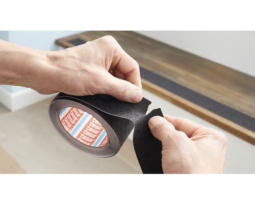 Person rollt Tesa Antirutschband aus, um es auf einer Treppenstufe anzubringen