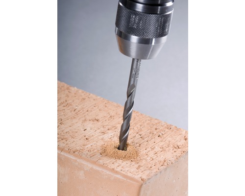 Nahaufnahme einer Bohrmaschine, die ein Loch in einen Ziegelstein bohrt.